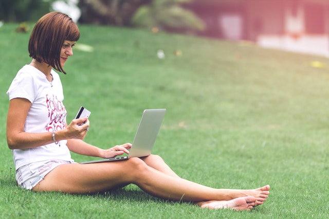 dívka sedí na trávě s notebookem na klíně